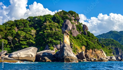 A vibrant coastal scene showcasing lush green hills, rocky formations, and a bright blue sky with fluffy clouds