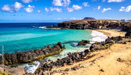 A vibrant coastal scene. Turquoise water laps a sandy beach, bordered by dark volcanic rock formations and arid landscape under blue skies