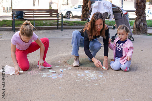 Generations family time, mother teaching children creativity with chalk drawing on playground