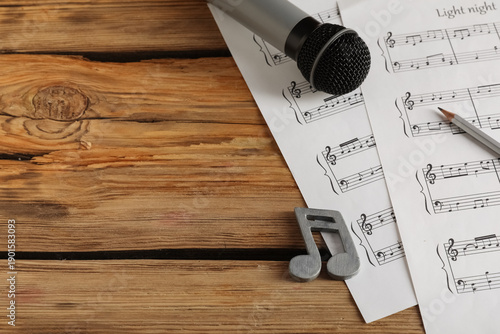 Paper sheets with notes, microphone, note sign and pencil on wooden background
