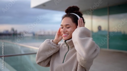 Wallpaper Mural Smiling diverse woman adjusting headphones after outdoor workout, relaxed posture, short rest moment, urban fitness lifestyle, recovery pause, positive mood, balance and wellness Torontodigital.ca