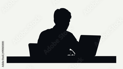 Silhouette of a Person Working on a Laptop at a Desk.