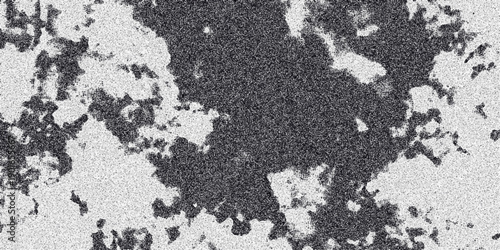 Abstract monochrome textured surface with irregular dark patches and a speckled grainy overlay creating a mottled organic pattern for backgrounds and artistic compositions