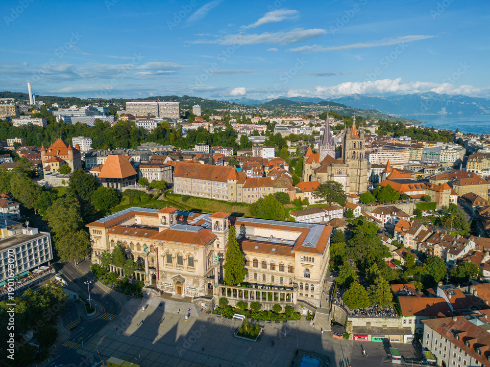 Obraz premium Aerial view of Lausanne featuring the historic old town, Lausanne Cathedral and surrounding cityscape with Lake Geneva and the Alps in the background, Switzerland