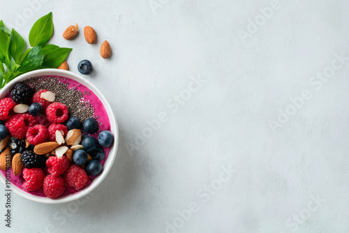 Healthy breakfast fruit berry smoothie bowl topped with fresh raspberry blueberry almond seed provides refreshing joyful mood against gray marble background with copy space for text