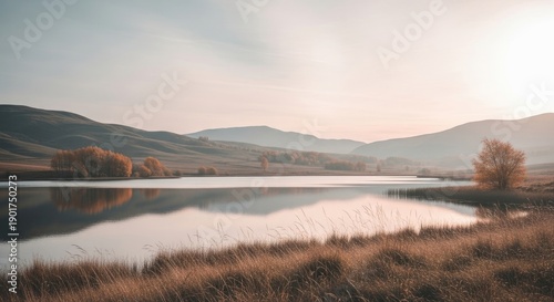 Panoramic view of a calm sunrise over the mountain lake and river mist reflecting a blue summer sky and forest landscape