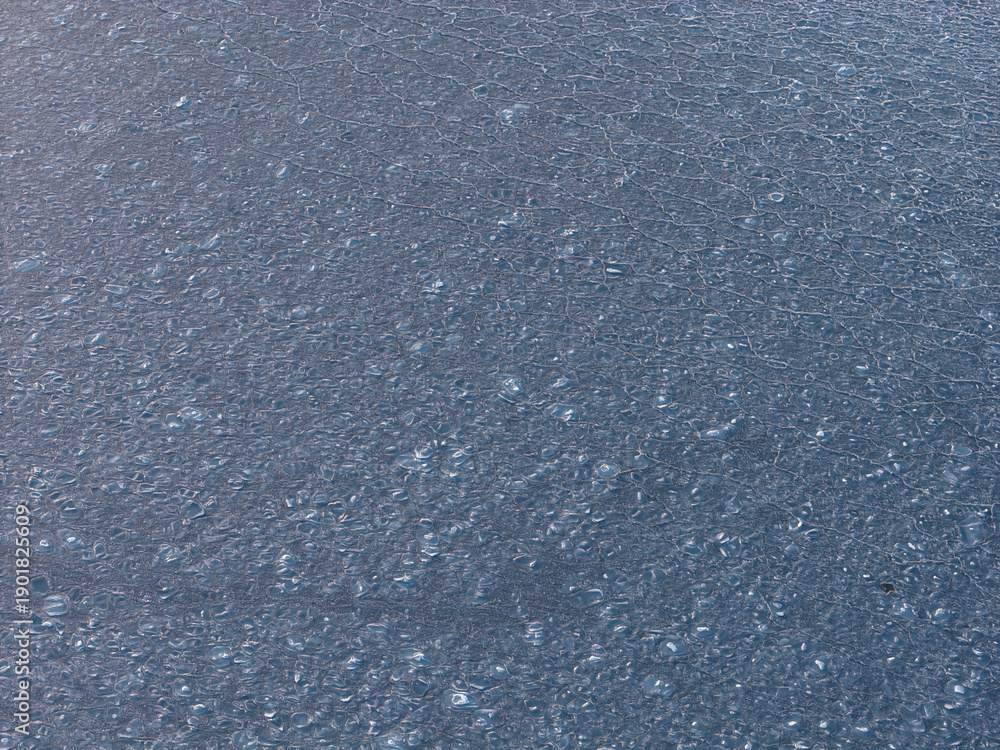 Fototapeta premium Water surface shows intricate patterns of refreezing ice crystals, creating a delicate frozen texture on the bay at plum beach point drive in port washington, new york