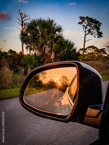 Sunset road reflected in car side mirror