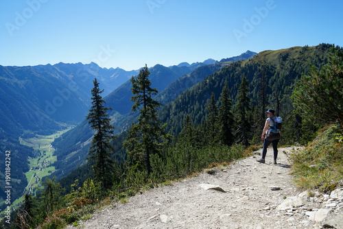 Young Mother Hiking with Child in Backpack Enjoying View of Schladming, Austria – Sunny Summer Day with Copy Space