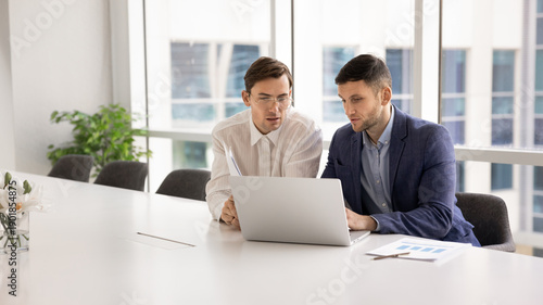 Tableau sur toile Two focused European company staff members working together on presentation usin