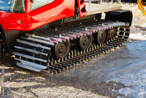Photos Red snow groomer vehicle with metal tracks parked on icy ground, showcasing deta