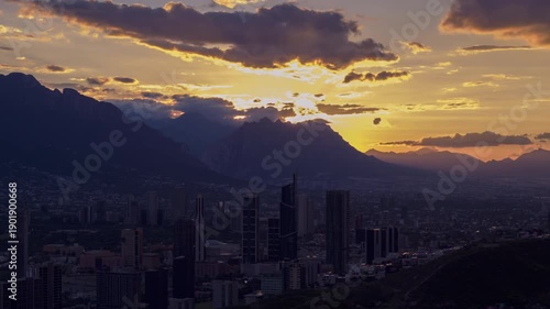 Aerial hyperlapse of modern city skyline at dusk with mountains and sunset