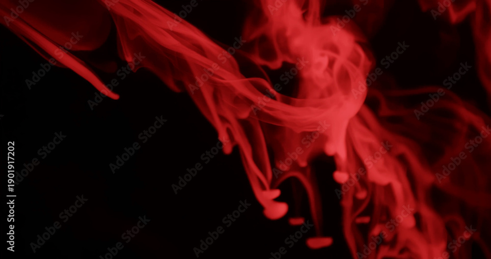 Obraz premium Ethereal red smoke swirls elegantly against a dark background, creating a mysterious and atmospheric scene.