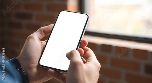 Close Up of Hands Holding Smartphone with Blank Screen against Brick Wall Background Near Window