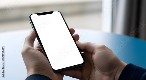 Close Up Shot Of Hands Holding Smart Phone With White Screen In Front Of A Blue Table