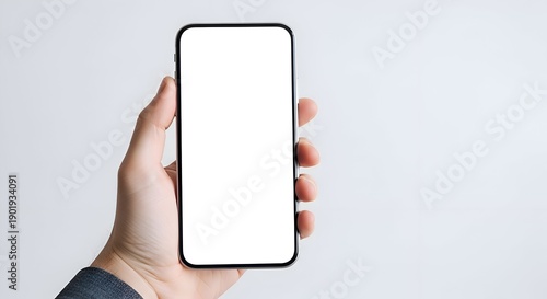 Male Hand Holding Modern Black Smartphone With Blank White Screen Against A Bright Plain Background
