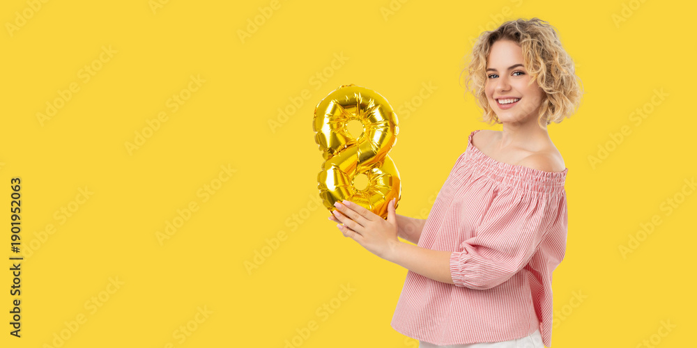 Fototapeta premium Woman smiles and holds a golden number balloon in celebration