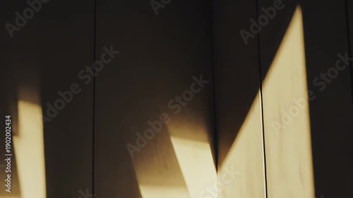 Warm sunlight illuminating an empty room corner, casting strong shadows on the textured wall and polished floor, creating a minimalist and serene atmosphere