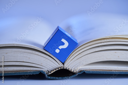 cube block with question mark on opened book