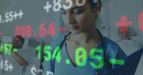 Checking nurse in blue scrubs with stethoscope using tablet at hospital bed overlaid stock numbers