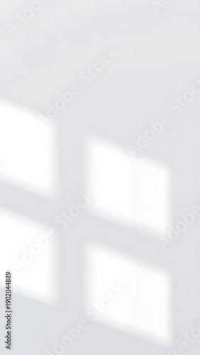 Shadows cast from window panes on a white wall, creating geometric patterns of light and shadow, evoking a sense of calm and simplicity