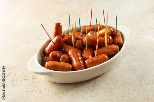 A view of a bowl of cocktail wieners with inserted rainbow toothpicks.