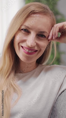 Woman with long hair smiles sincerely while sitting at home in a relaxed setting.