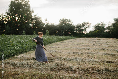 Photography Ukrainian woman raking hay in a rural village field