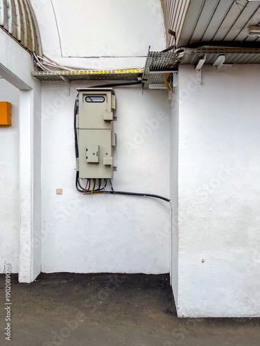 Fényképezés Electrical meter panel and cable box mounted on a white building wall, showing neat wiring, functional layout, and clean infrastructure design in an outdoor service area