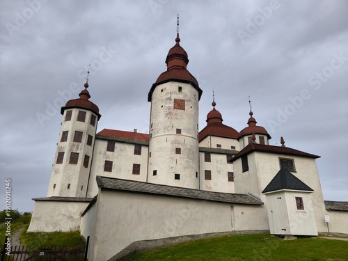 Lacko Castle, Sweden - August 29th 2024: View of Lacko Castle featuring white stone walls, round towers with red roofs and an arched entrance under an overcast sky in Sweden