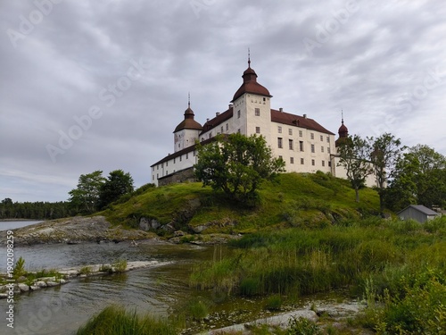 Lacko Castle, Sweden - August 29th 2024: View of Lacko Castle featuring white stone walls, round towers with red roofs and an arched entrance under an overcast sky in Sweden