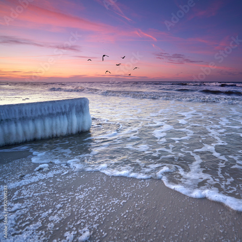 frozen pier with icicle with rushing waves at Baltic Sea beach