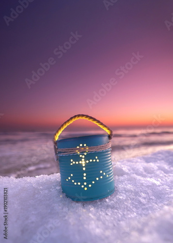 Homemade tin can lantern with anchor on the beach in winter