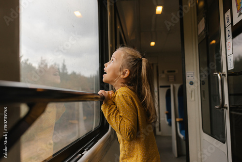 Child looking out rainy train window experiencing daily travel