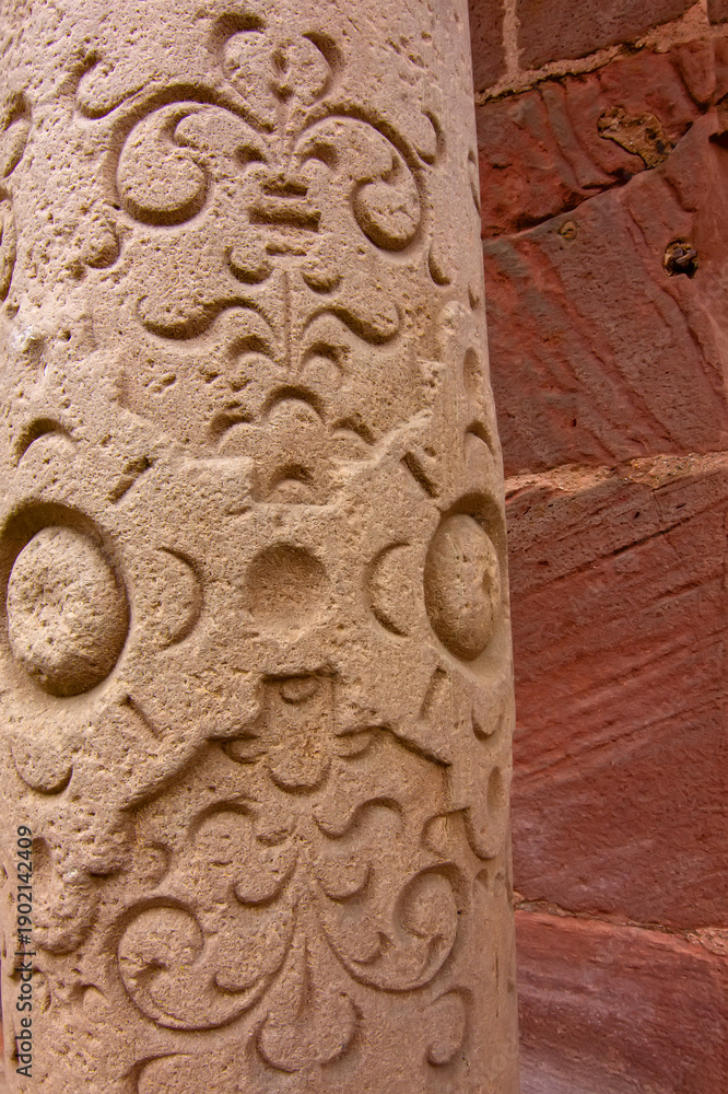 Fototapeta premium Close view of carved Gothic church pillar showing medieval faces and stone ornament.