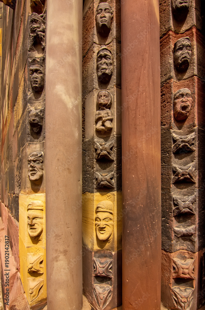 Fototapeta premium Close view of carved Gothic church pillar showing medieval faces and stone ornament.