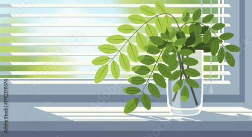 Green leaves in a glass vase sit on a windowsill with blinds