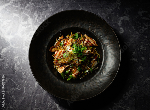 A plate of food with a black bowl and a green garnish