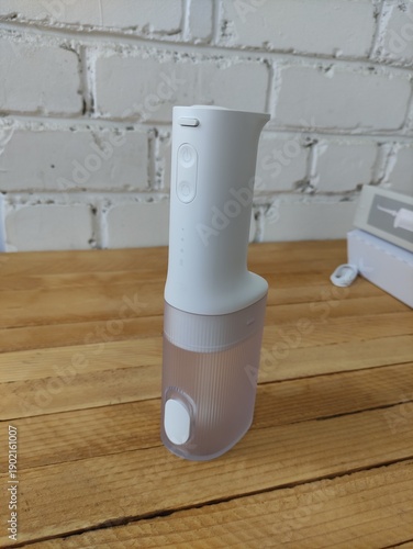 White oral irrigator for dental care on wooden surface