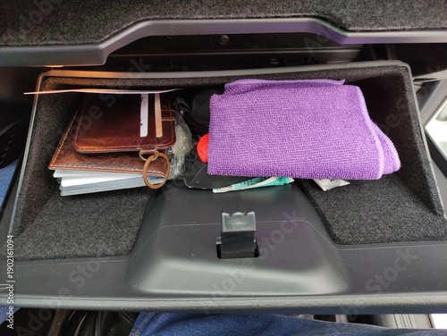 Open car glove compartment with various driver essentials inside