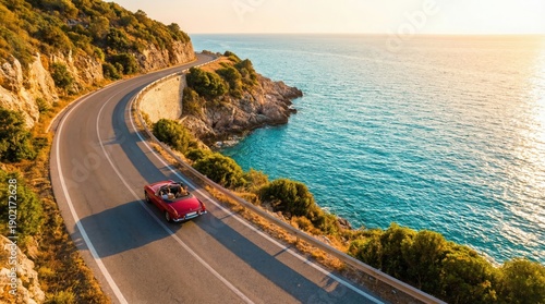 Couple driving red convertible classic car on winding coastal road at sunset. Aerial view of romantic road trip by the sea