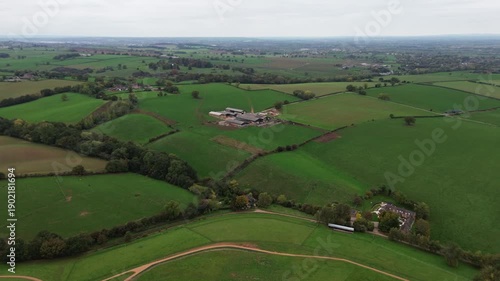 Aerial drone footage pushing in over a rural cow farm in Derbyshire, England, showing farmland and fields. Suitable for agriculture, rural business, sustainability, and countryside establishing shots.