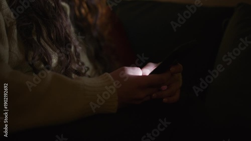 close up of a person scrolling on a smartphone in a dark room, with screen glow illuminating hands and face, representing late night screen time digital habits and modern technology lifestyle concepts