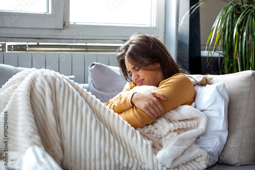 Foto Woman feeling cold and shivering on sofa