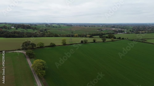 Drone aerial footage panning right around power lines and pylons in Derbyshire, England, suitable for energy infrastructure, utilities, transmission, business, and establishing background shots.
