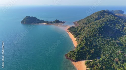 Aerial view of tropical coastline with lush jungle hills, sandy beaches, and clear blue sea surrounding peaceful Koh Phayam island.