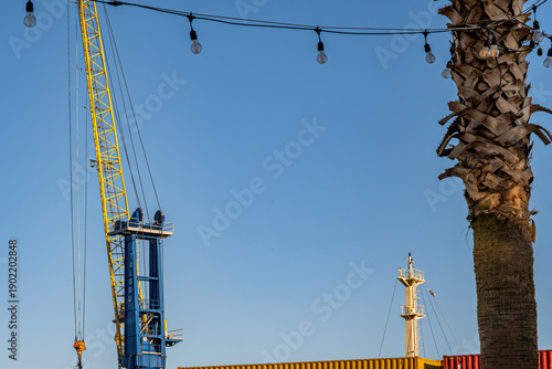Silhouette of a port crane against stacked shipping containers. Industrial and logistics concept. Maritime transport, cargo handling, and shipping industry