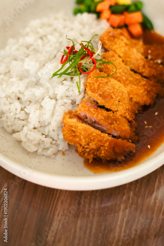 Japanese chicken katsu curry with rice and vegetables served on plate, crispy fried cutlet with rich curry sauce.