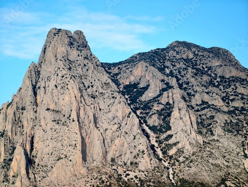 Fotografie Dark narrow path winding through towering stone peaks under dramatic late daylig