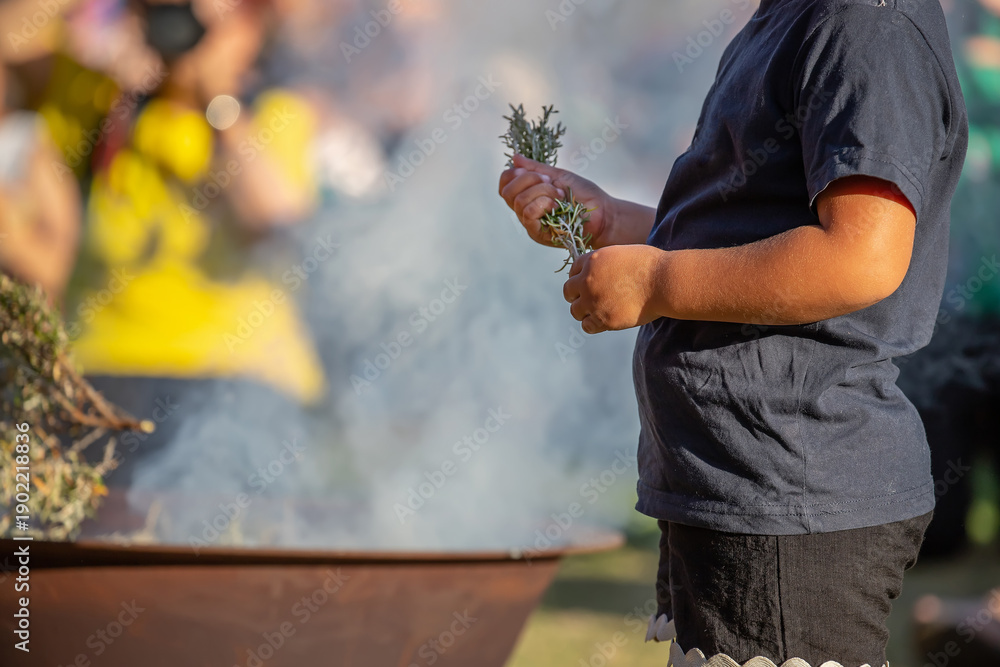 Fototapeta premium Kid hands with green branches, smoking ritual dish, Australian aboriginal smoking ceremony, ritual rite at an indigenous community event
